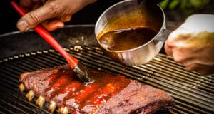 Kugelsmoker – verwandle deinen Holzkohlegrill in einen Smoker Ribs mit BBQ Sauce einpinseln